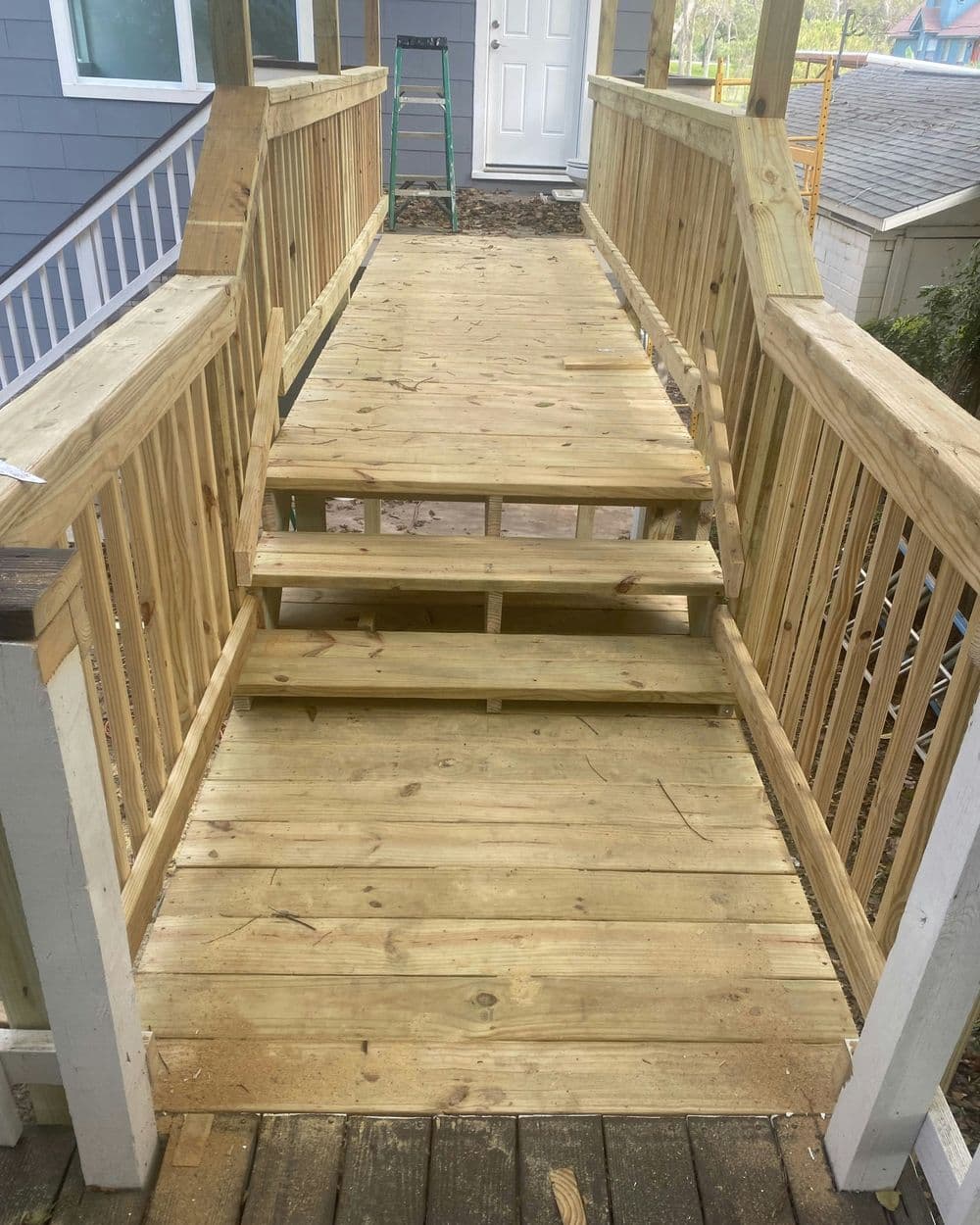 Newly built wooden ramp and steps leading to a house entrance, featuring sturdy railings.